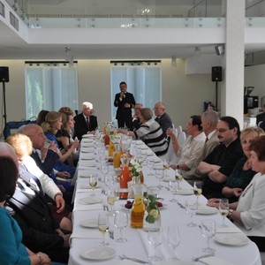 siedzące osoby przy stolikach i przemawiającego Wójta 